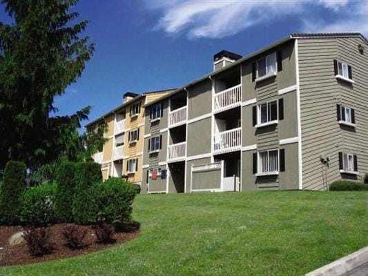 apartment Row of apartment buildings on the right with a grass lawn in the foreground. There is a tree on the left hand side.